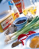 Various Asian ingredients - garlic, ginger, chilli peppers, oil and spring onion