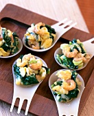 Spoon food with spinach, crabs and scrambled eggs on wooden platter