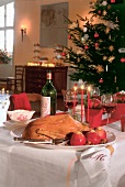 Roast goose with roasted apples on plate on a festively decorated table for Christmas