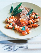 Schnitzel with white beans and sage leaves on plate