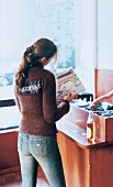 Rear view of woman in knitted sweater and jeans standing in a record store before DJ desk