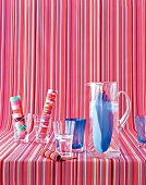 Glasses and decanter on fabrics stripped background