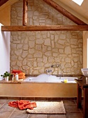 Bathtub in front of stone wall in bathroom