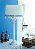 White table lamp with beads at bottom screen edge and figurines on table