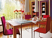 Large dinning room with pink chairs and rose stand on long table