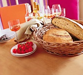 Brot in einem Korb, im Hintergrund Weingläser und Weinflaschen