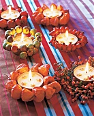 Maxi-Teelichter mit verschiedenen Fruchtkränzen dekoriert