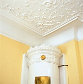 White Swedish fireplace with stucco ceiling decorated with rich ornament