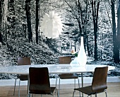 Table and chairs against black and white wallpaper with forest motif