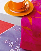 Rot - orange Tischdecke daneben ein oranges Geschirr