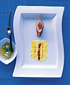 Caramelized breast of guinea fowl with pineapple, carpaccio and sauce on plate