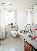 View of bathroom with toilet seat, mirror over sink and marble tiled floor