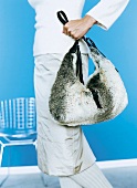 Frau trägt grau-weiße Fellhandtasche mit dunklem Lederriemen