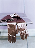 Ellenlange Handschuhe aus Satin liegen auf einem Stuhl