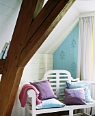 weiße Holzbank mit pastellfarbenen Kissen.