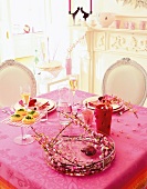 Laid dining table with pink table cloth and decorations