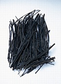 Close-up of dried haricots vert shaped seaweed on white background