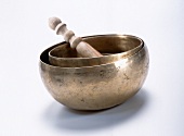 Close-up of singing bowls and wooden clapper on white surface