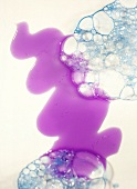 Pink hair shampoo mixed with water turning blue on white surface
