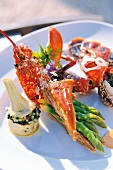 Close-up of lobster salad with stuffed artichoke and green asparagus on plate