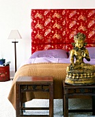 Schlafzimmer im asiatischen Stil Bett, Buddha-Statue, rotes Polster
