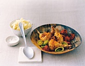 Braised baby turkey legs, leek, tomato and mashed potatoes in wooden bowl