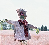 Scarecrow with cord cap, scarf, knitted sweater, corduroy jacket in field