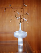 Branches of flowers in white vase on table