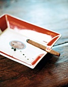 Lit cigar on ceramic ashtray