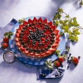 Tart with vanilla cream and toppings of different berries with icing sugar