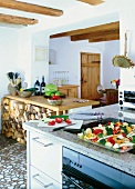 Vegetables on plate, stack of firewood, stove and timber furniture in rustic kitchen