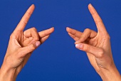 Close- up of woman's hand performing acupressure mudra against blue background