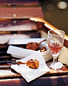 Crispy chicken legs and glass of red wine for picnic on jetty