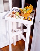 Box of fruits on white glued small wooden table with ceramic tile