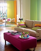 View of living room with colourful pillows on sofa and purple foot rest