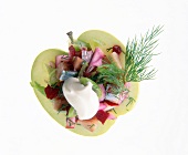 Close-up of matjes, gherkins, beetroot and dill in hollowed apple on white background