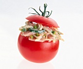 Close-up of stuffed tomato with farmer salad, roast pork and pistachio nuts