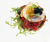 Close-up of tatar with hack quail egg, lettuce and rye bread on white background