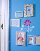Colourful picture frame hanging on blue wall painted with flower