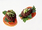 Close-up of baguette slices with meatballs, tomatoes and green onions on white background