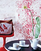 Eine Tapetenbahn mit opulentem Muster, rot-weiß, Stuhl + Tasche