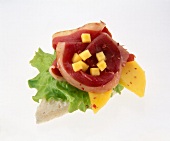 Close-up of sandwich bread with goose breast, mango and lettuce on white background