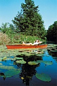 Frau liegt entspannt im Paddel Boot umringt von See - Rosen