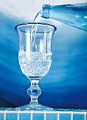 Wasser wird in ein Glas gekippt, blau