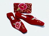 Floral embroidered velvet slippers and purse on white background