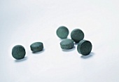 Six green seaweed tablets on white background