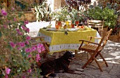 Bunt gedeckte Sommertisch mit gelben und roten Gläsern, gelber Tischdecke