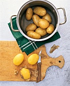 Gekochte Kartoffeln in Topf,daneben frisch gepellte Kartoffeln.Step1