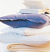 Close-up of several cushion placed one above other with book on top