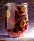 Plum, berries, cloves and candy with plum brandy in glass jar